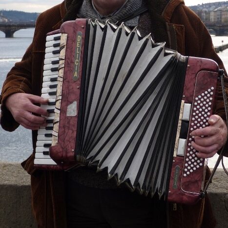 a person playing a red accordion in front of a river